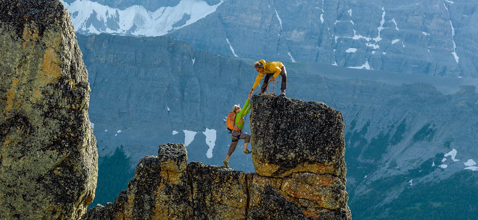 mountaineers scale rocks steps on cliff with rope